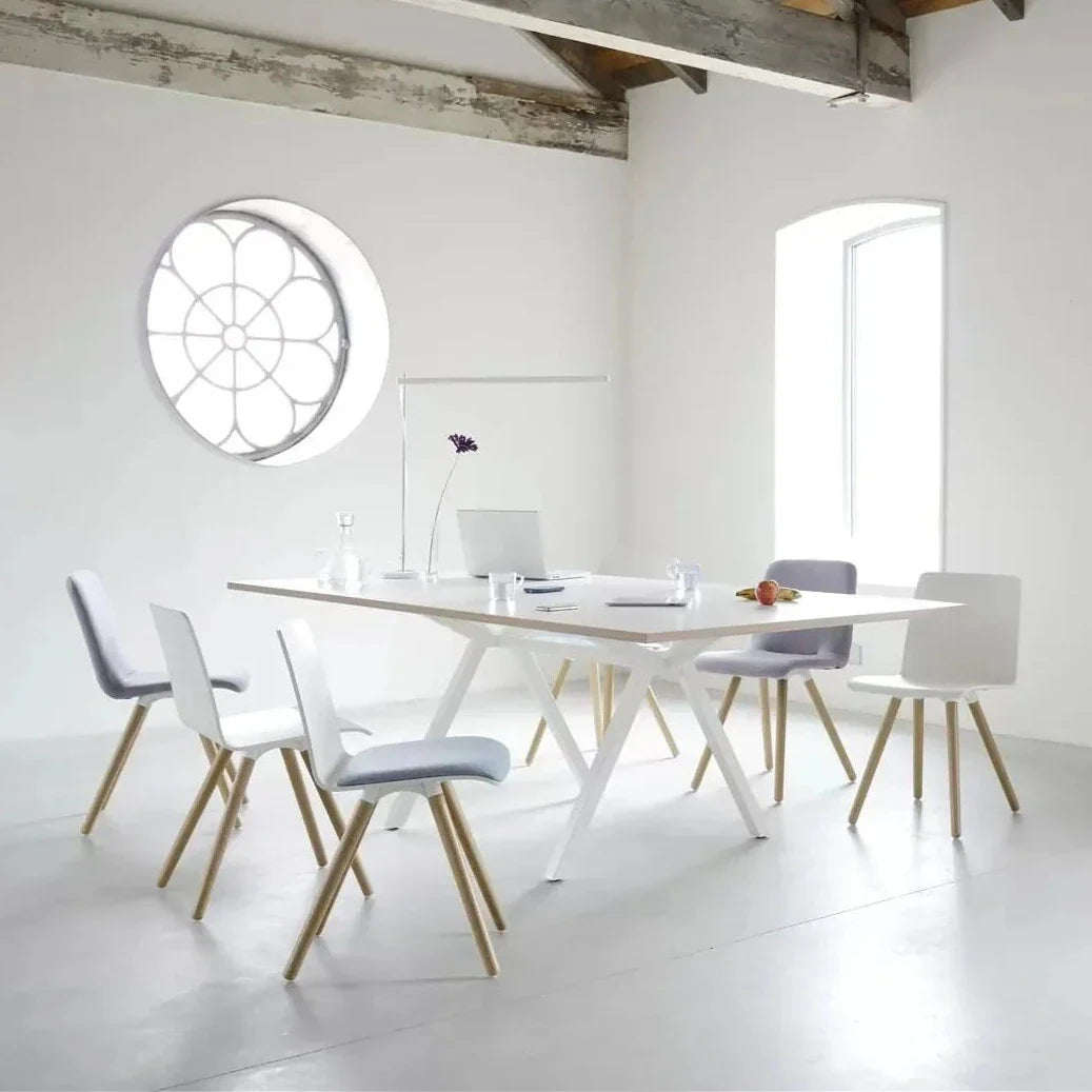 Witte vergadertafel met vier stoelen en een rond raam, ideaal voor een moderne werkomgeving en samenwerking.