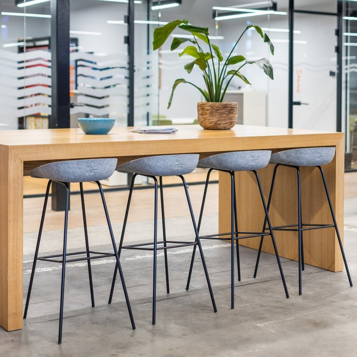 Tafel met vier stijlvolle hoge krukken van gerecycled PET en een mooie plant, ideaal voor een duurzame inrichting.