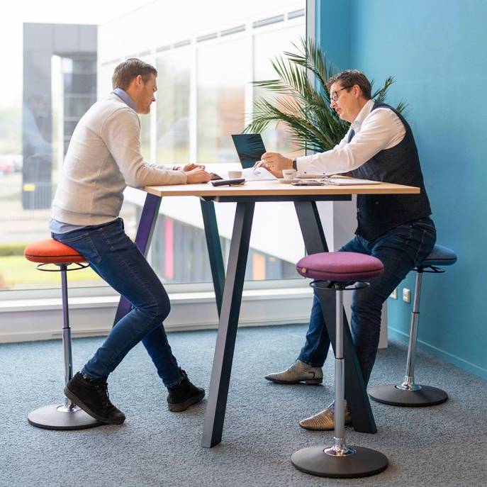Twee mensen zitten comfortabel op VILT Steady krukken aan een counter, ideaal voor een actieve werkplek.