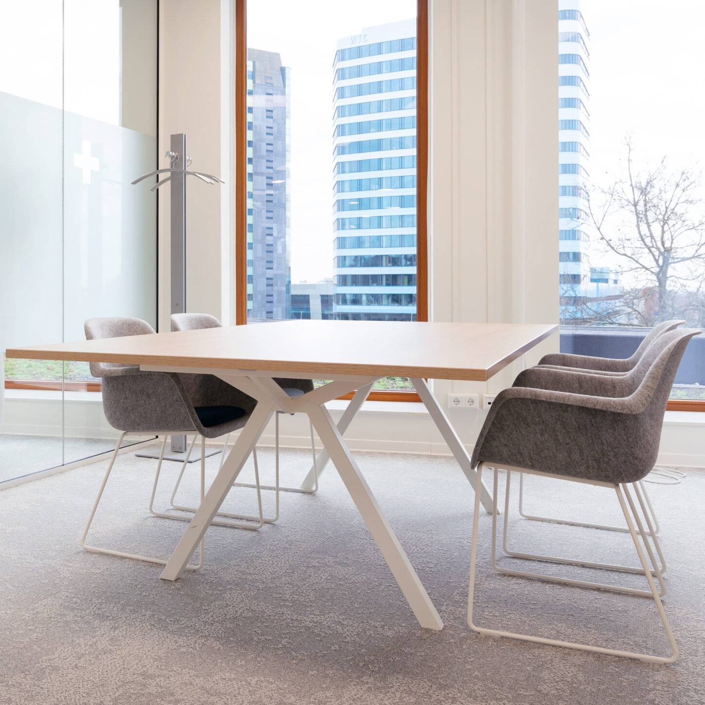 Een vergadertafel met stoelen voor een groot raam, perfect voor samenwerking en flexibele werkruimtes.