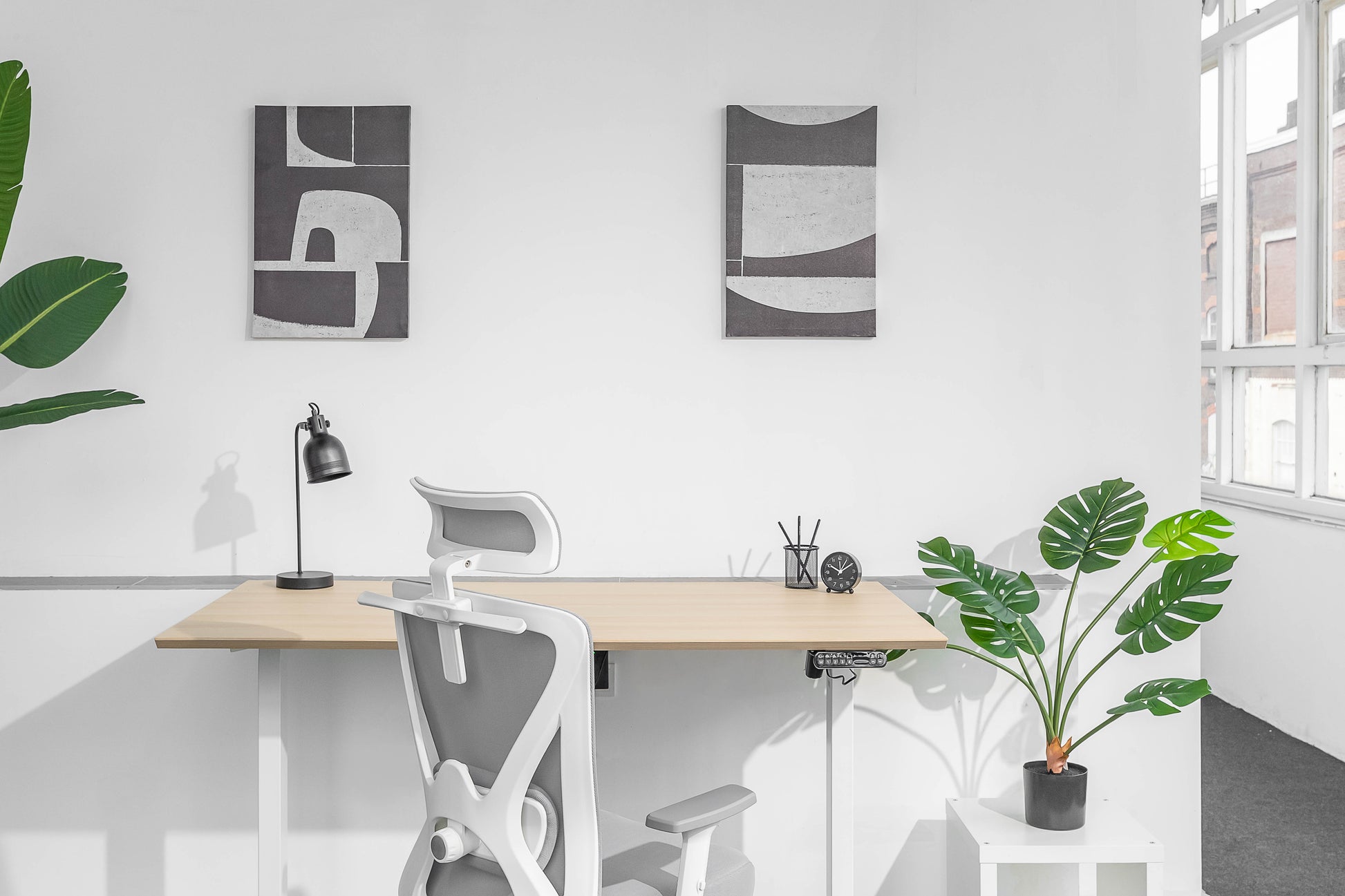 Een wit bureau met een plant en een bureaustoel, perfect voor een comfortabele werkplek.