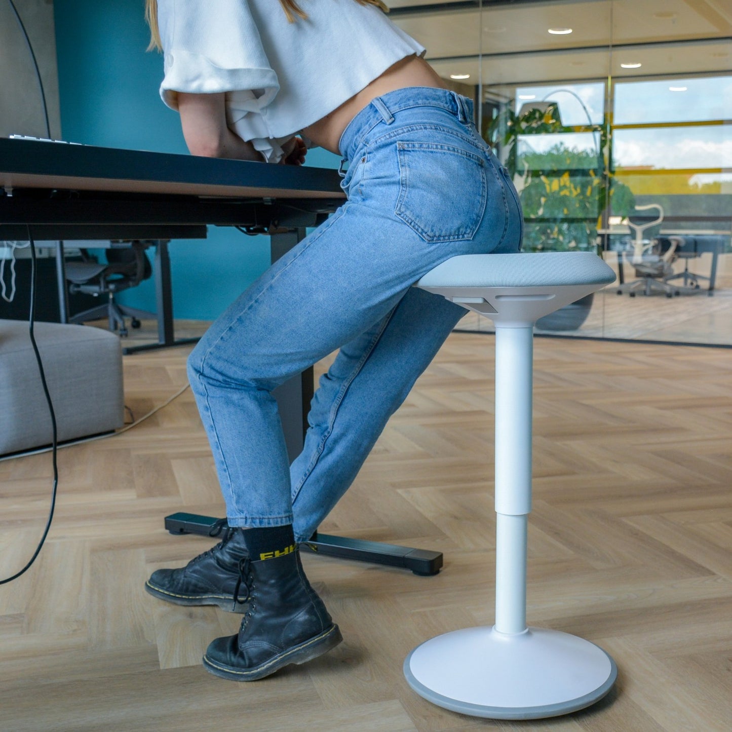 Een vrouw op een wiebelkruk aan een bureau, genietend van een comfortabele en duurzame werkplek.