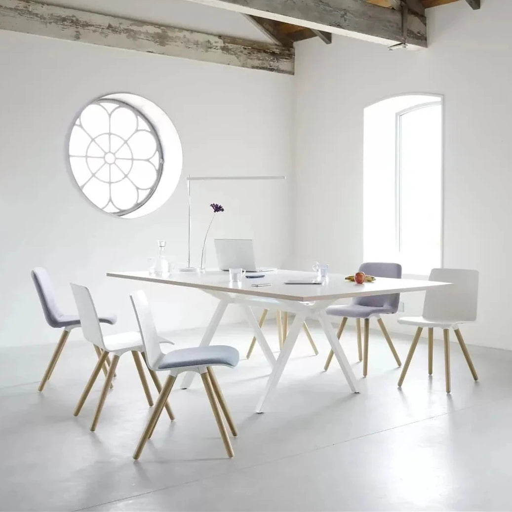 Witte vergadertafel met vier stoelen en een rond raam, ideaal voor een moderne werkomgeving en samenwerking.
