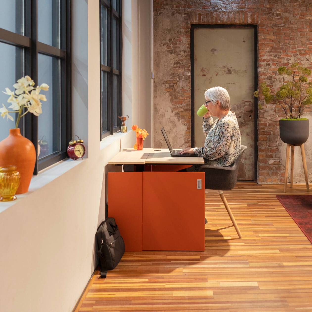 Vrouw aan een bureau in een kantoor, genietend van haar HomeFit thuiswerkplek.