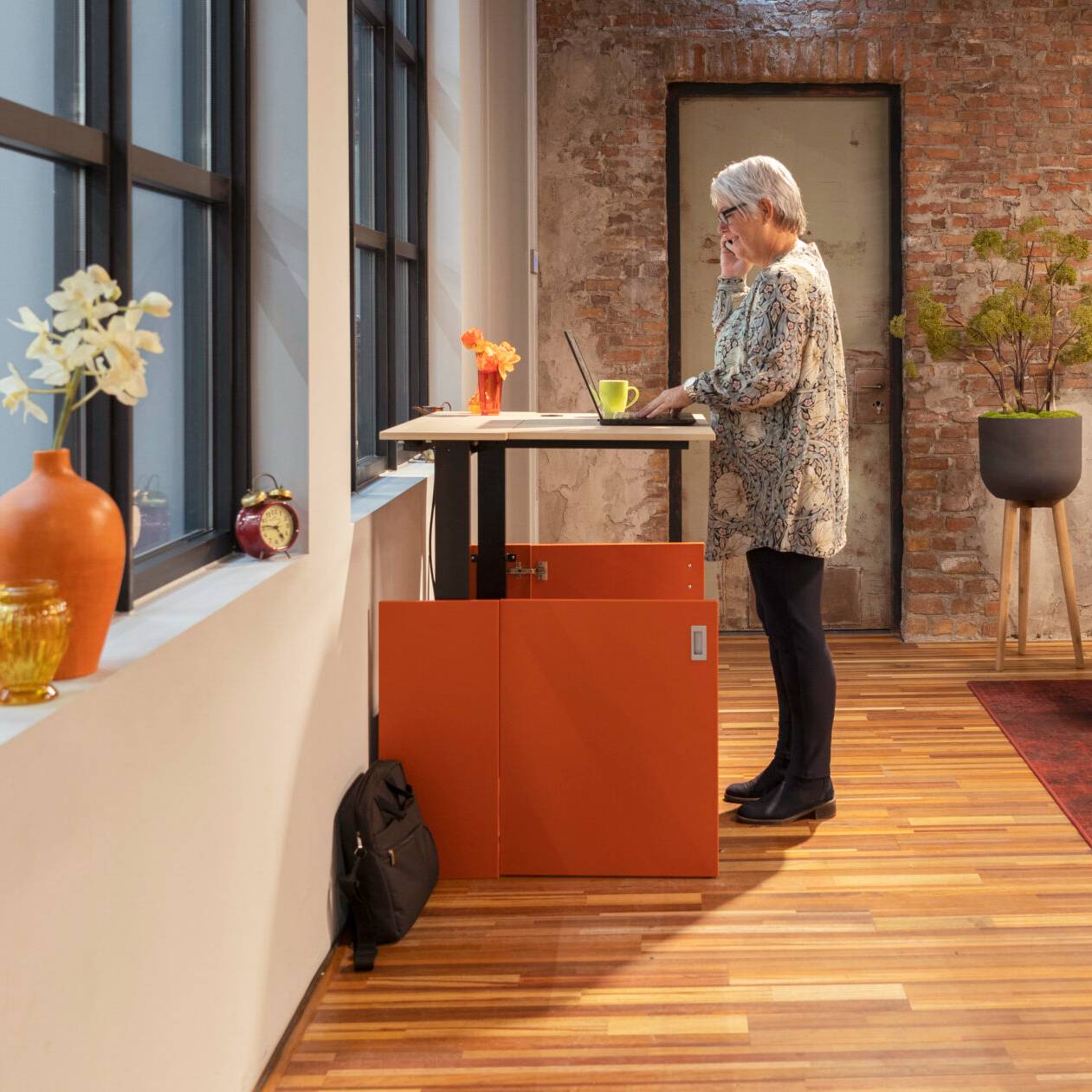 Een vrouw voor een bureau met computer in de HomeFit thuiswerkplek, gefocust op haar werk.