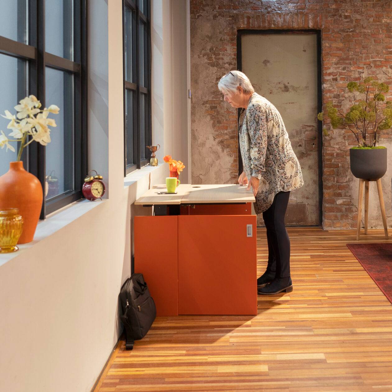 Een vrouw staat voor een bureau met een computer in de HomeFit thuiswerkplek.